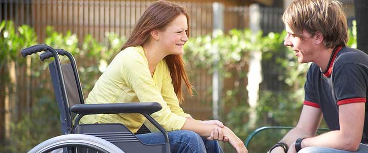 Ein Mädchen im Rollstuhl spricht mit einem Jungen im Park.